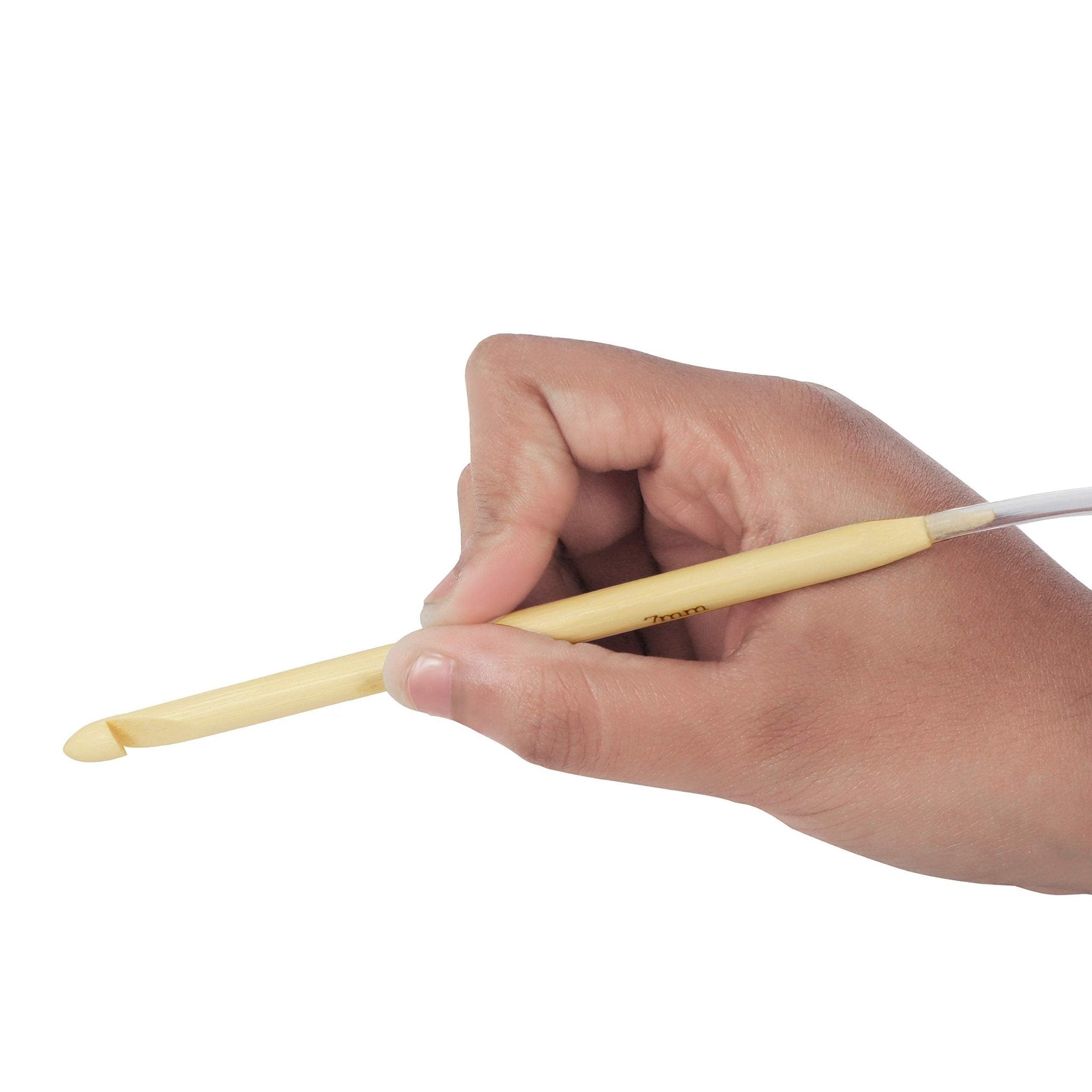 Hand holding a bamboo Tunisian crochet hook with a plastic cable attached, showing the 7mm size marking.
