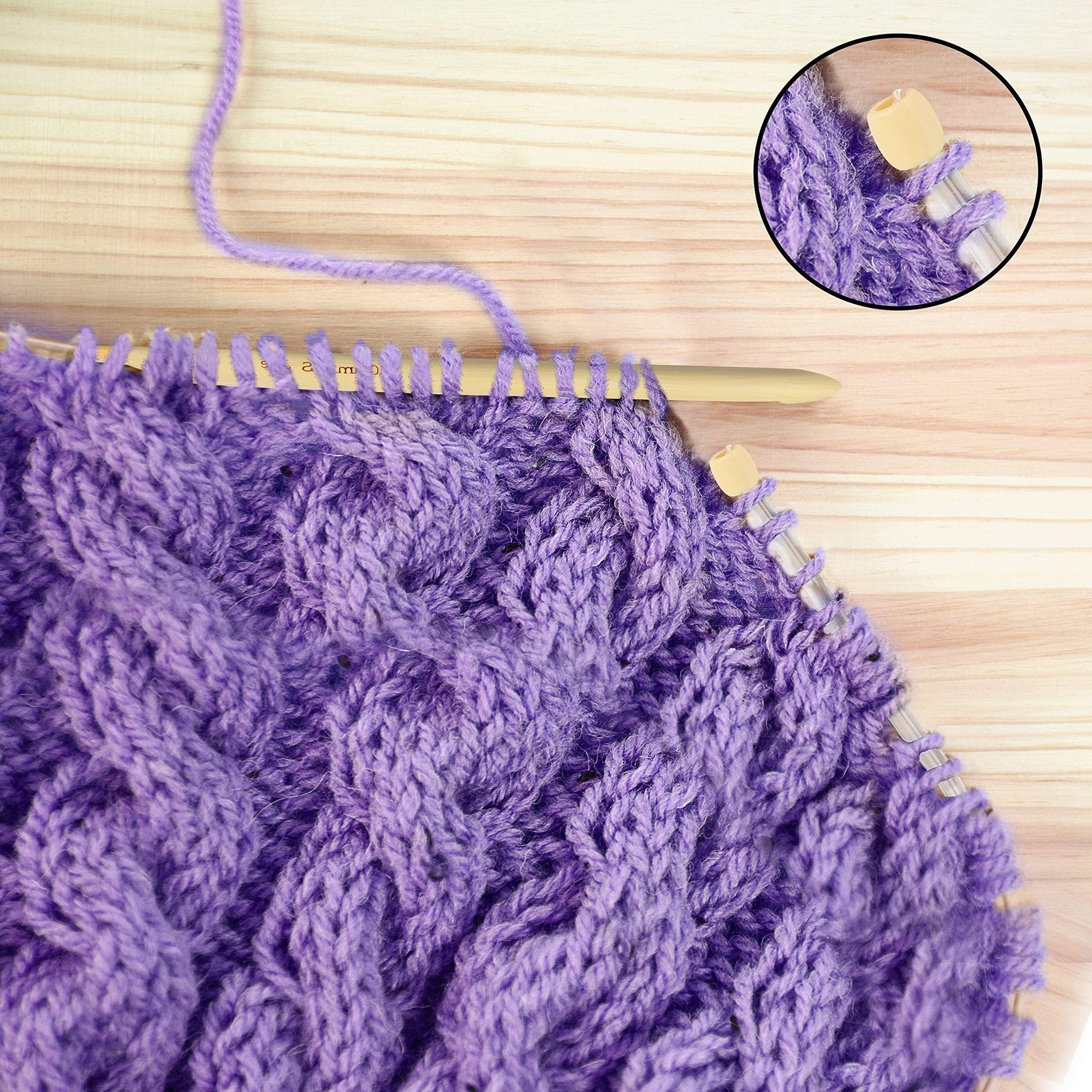 Close-up of purple cable knit fabric with bamboo crochet hook and yarn. Inset shows detail of hook and stitches.