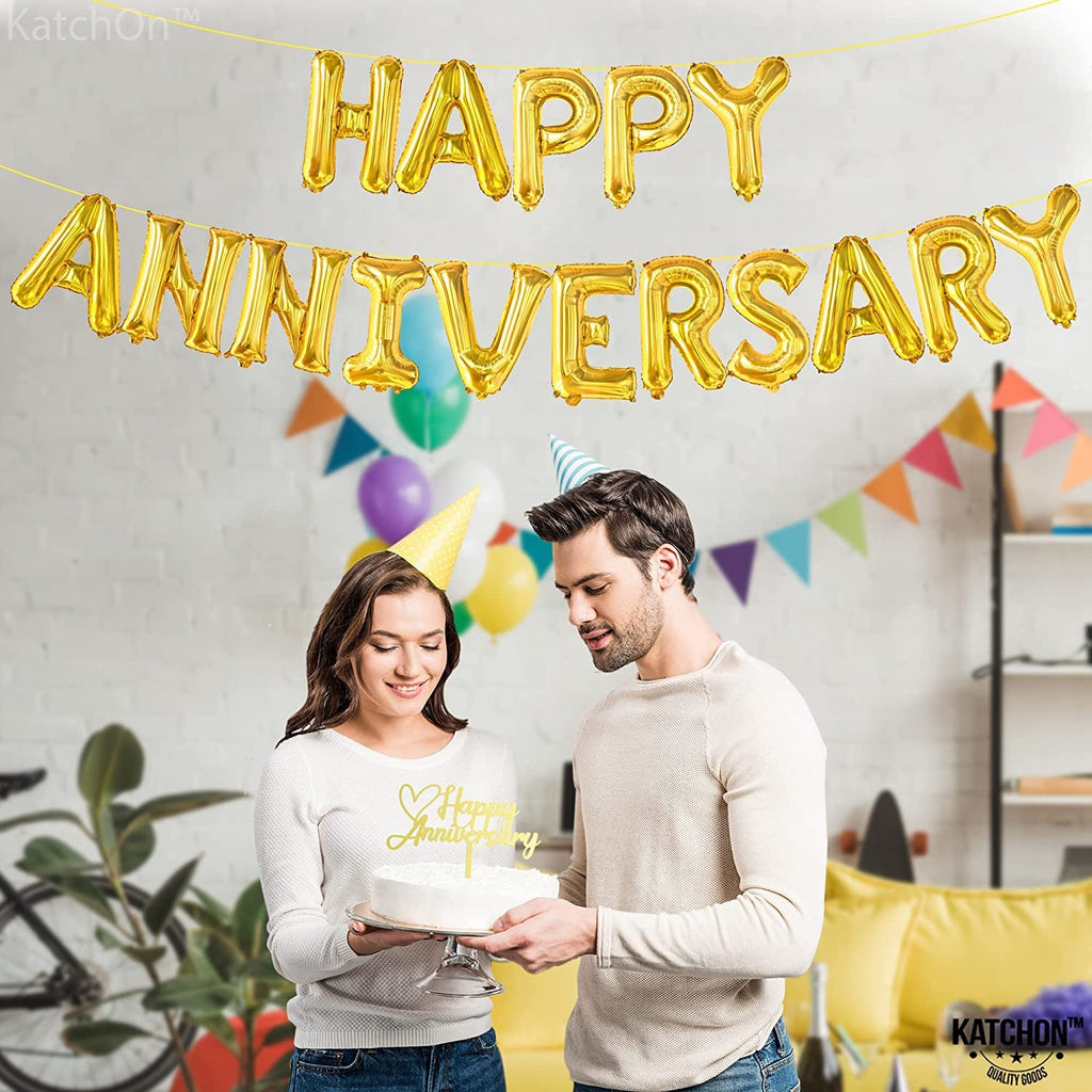 Couple celebrating anniversary with gold letter balloons and cake