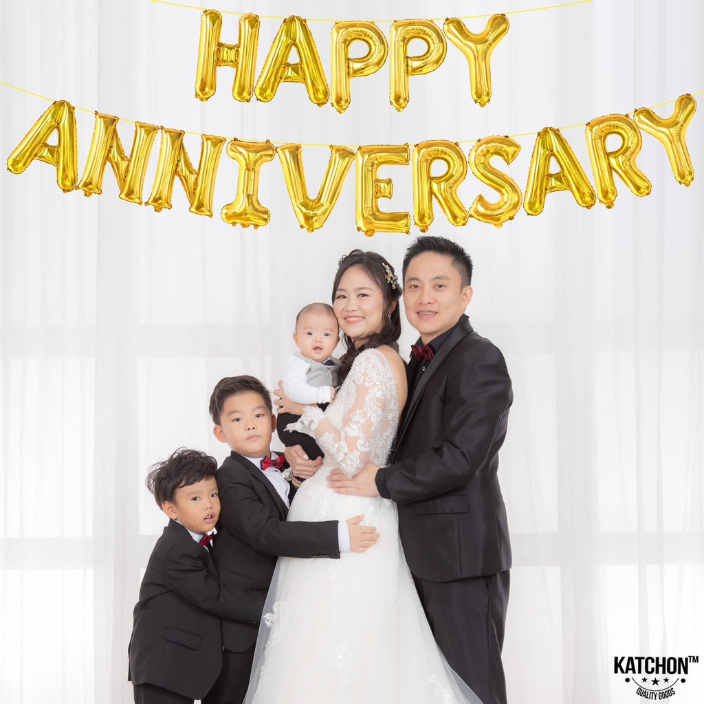 Family posing for anniversary photo with gold foil balloons spelling Happy Anniversary