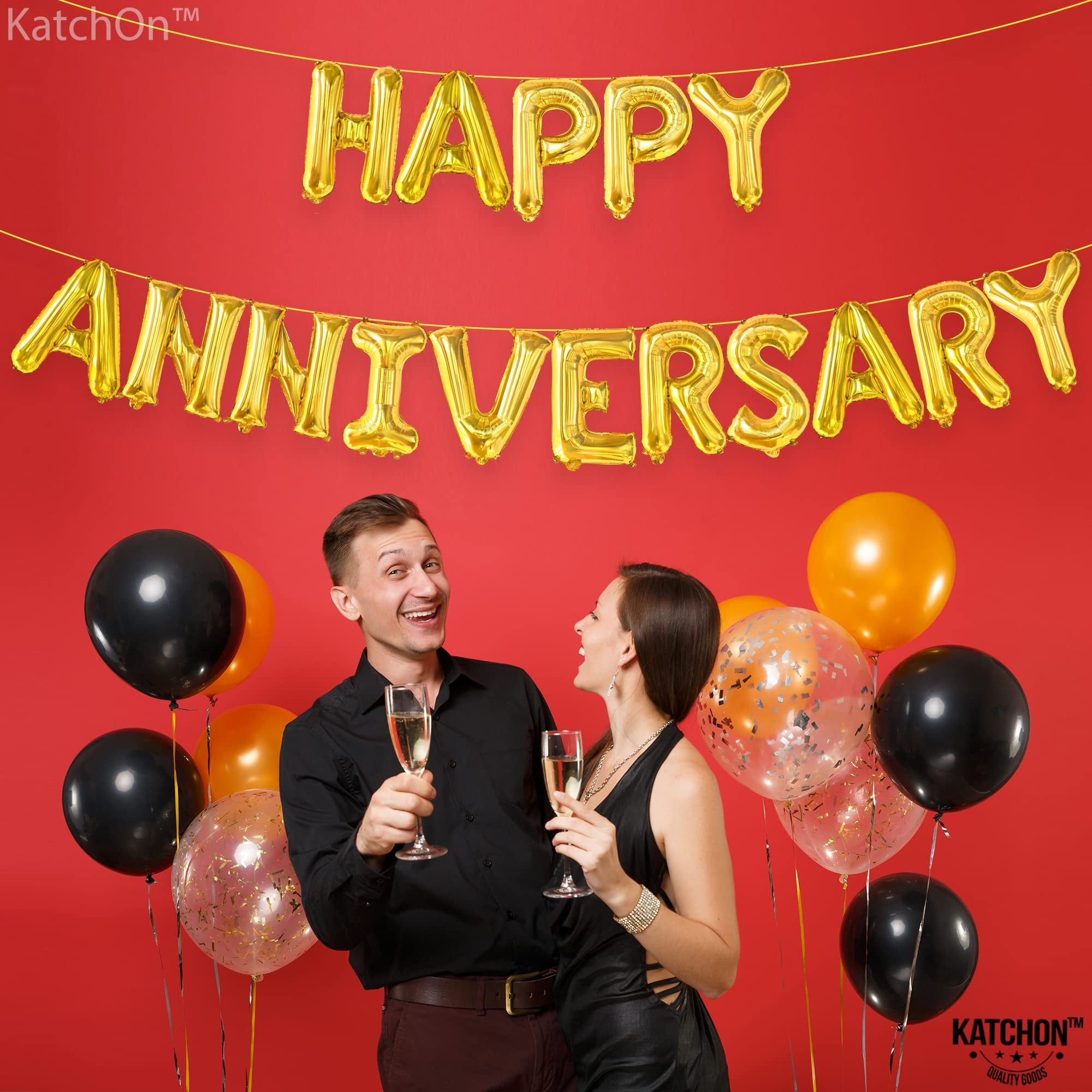 Couple celebrating anniversary with gold letter balloons and black and orange balloons