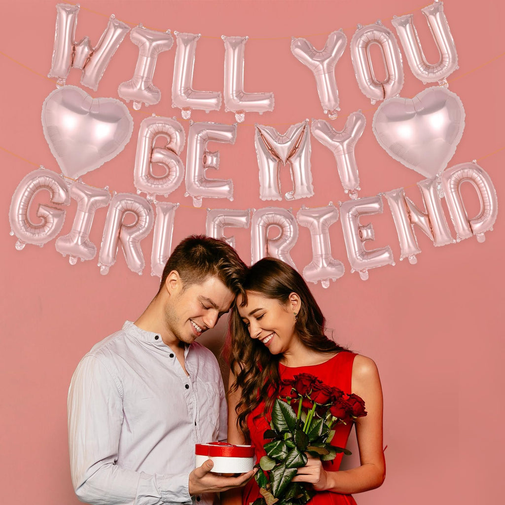 Couple with rose gold foil balloons spelling 'Will You Be My Girlfriend' for a proposal.