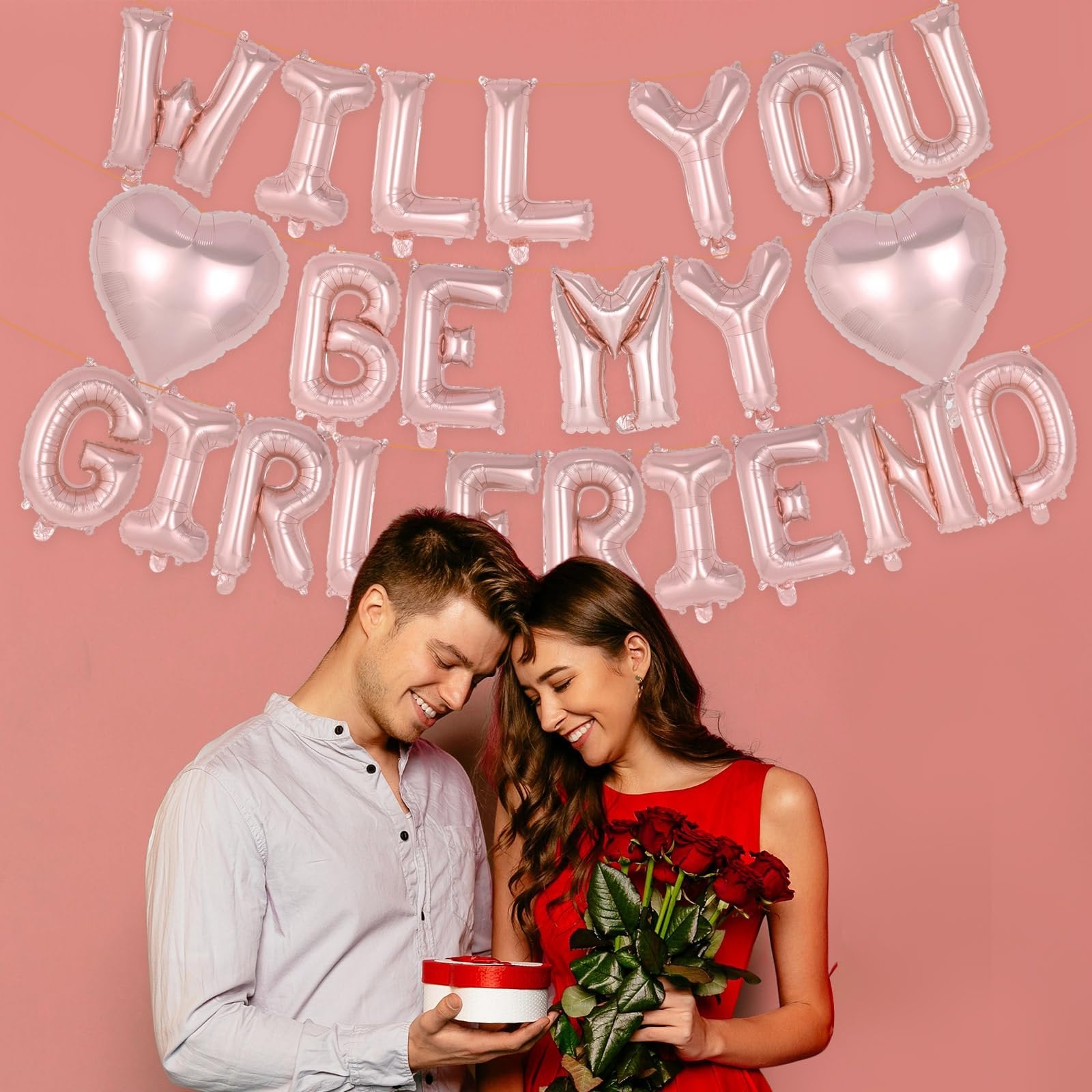 Couple with rose gold foil balloons spelling 'Will You Be My Girlfriend' for a proposal.