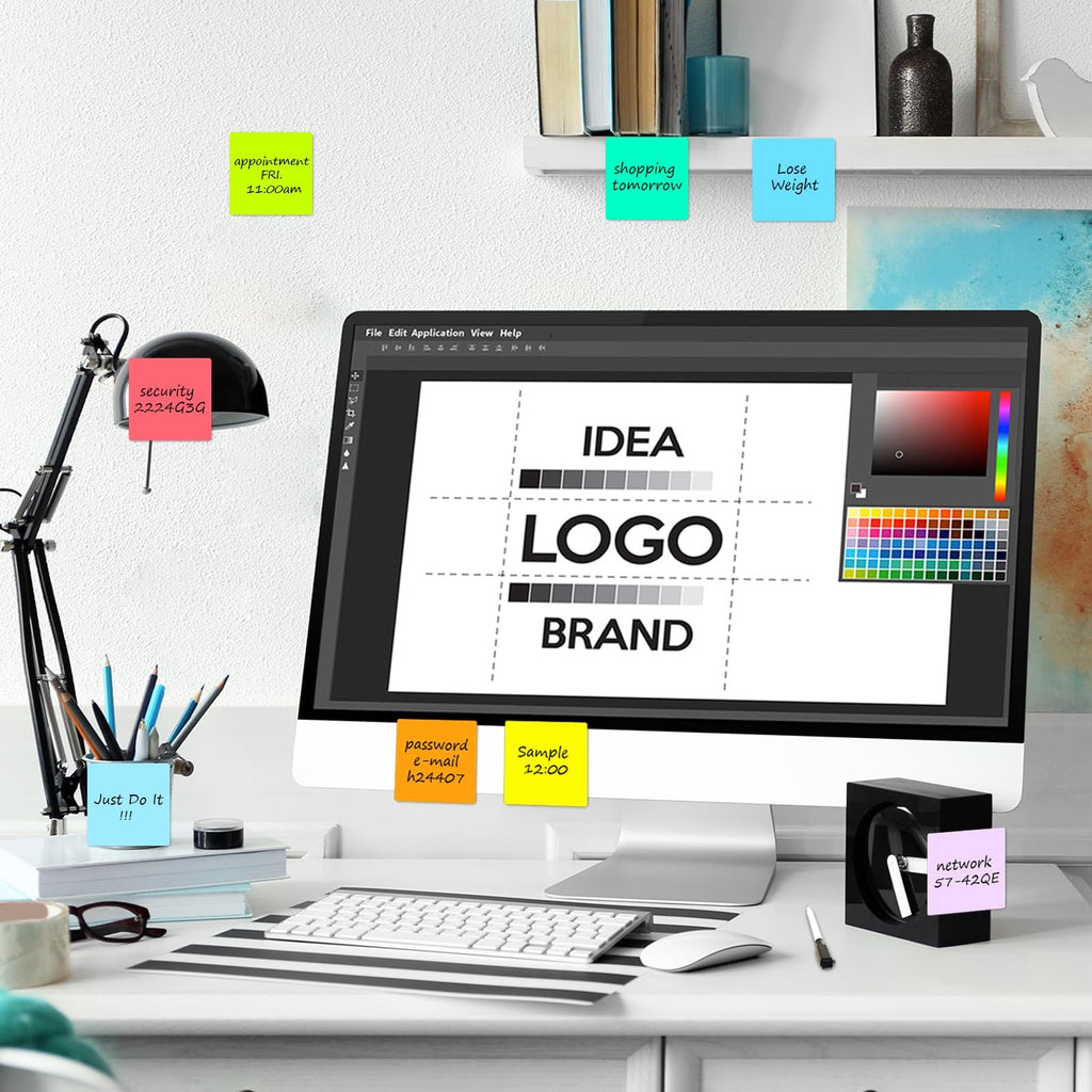 Desk setup with a computer displaying a logo design grid, surrounded by colorful sticky notes with reminders.