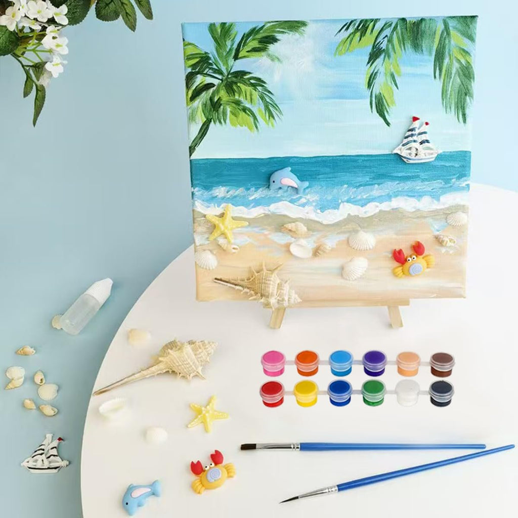 Beach scene painting kit with canvas, paints, brushes, shells, and sea creatures on a table.