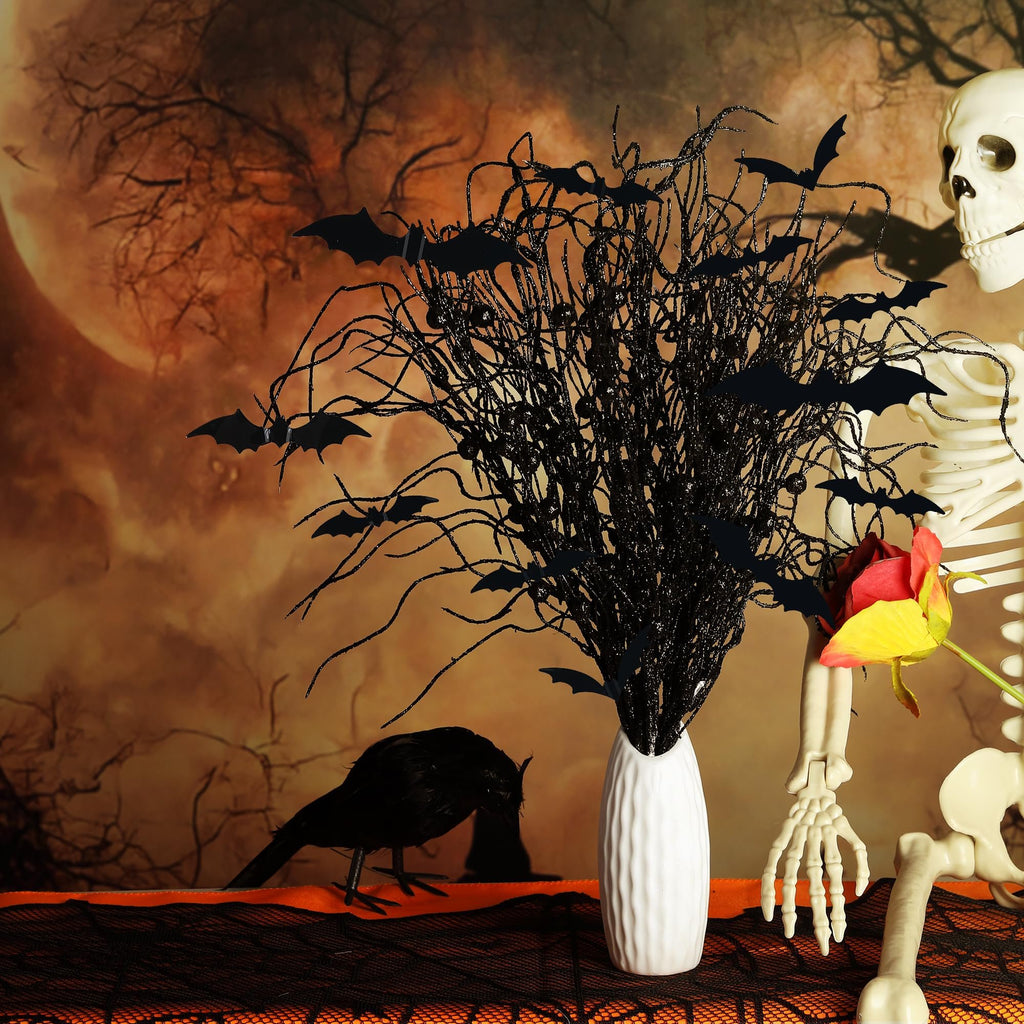 Halloween arrangement with black glitter branches, black bats, a white vase, a skeleton, a crow, and a rose against a spooky moon backdrop.