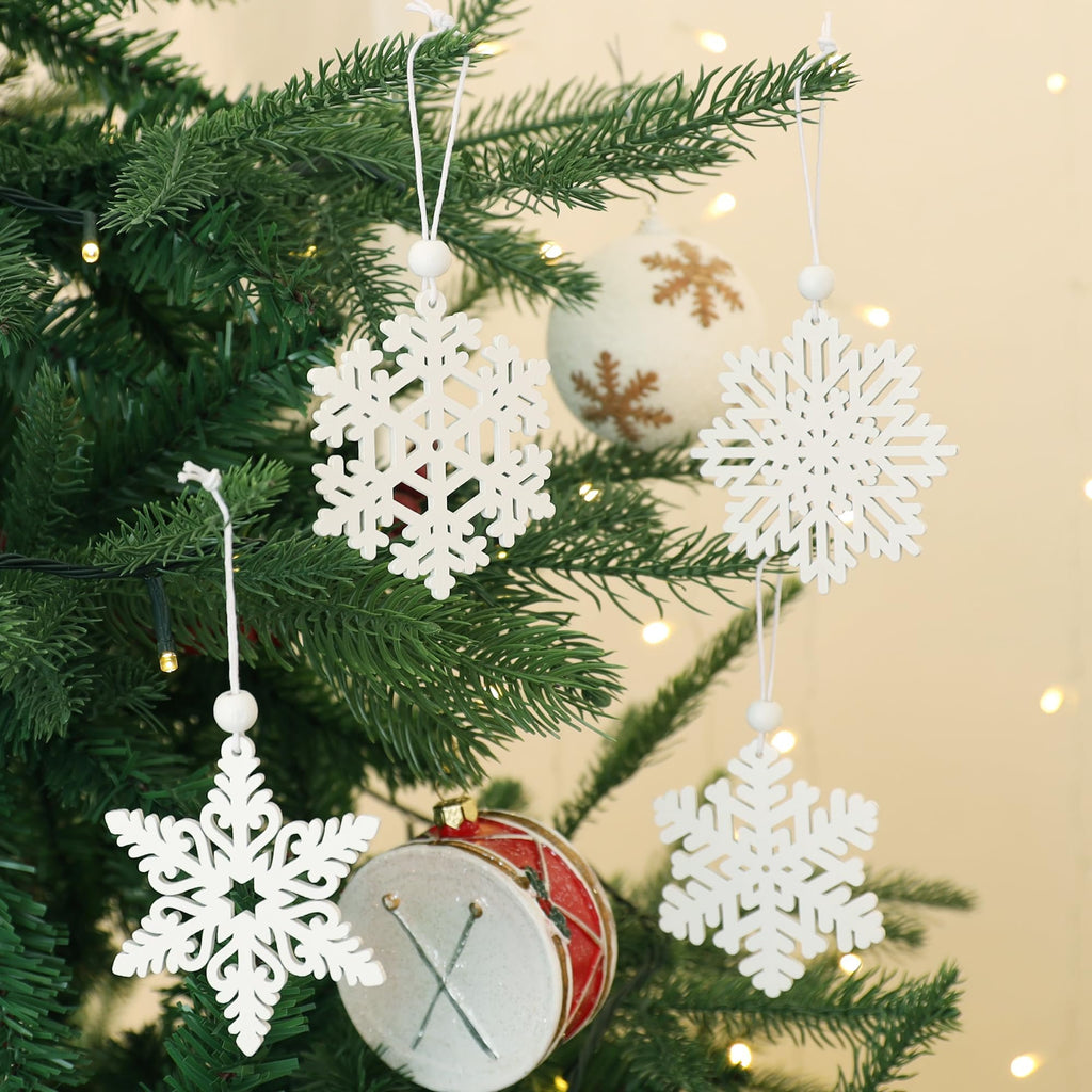 White wooden snowflake ornaments hanging on a Christmas tree with lights and a drum ornament.