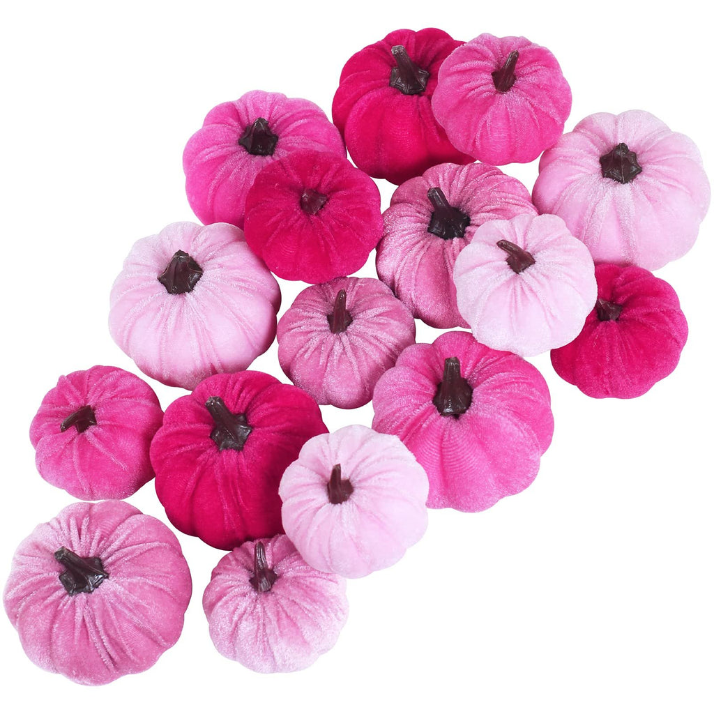 Assorted pink velvet pumpkins scattered on a white background