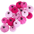 Assorted pink velvet pumpkins scattered on a white background