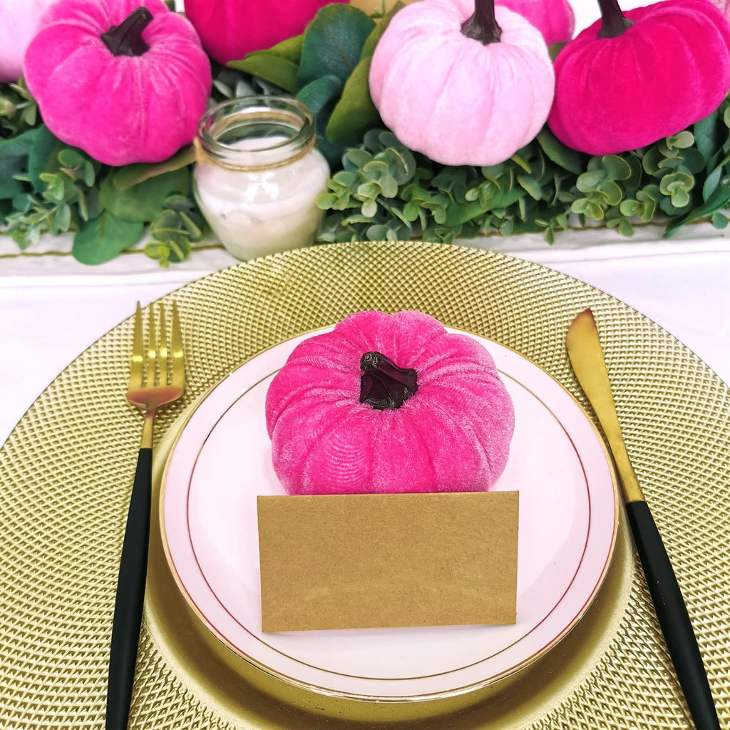 Velvet pumpkins arranged on a table setting with a place card on a plate.