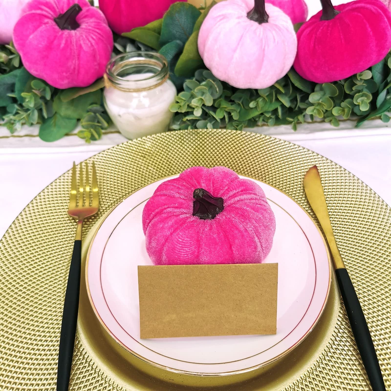 Velvet pumpkins arranged on a table setting with a place card on a plate.