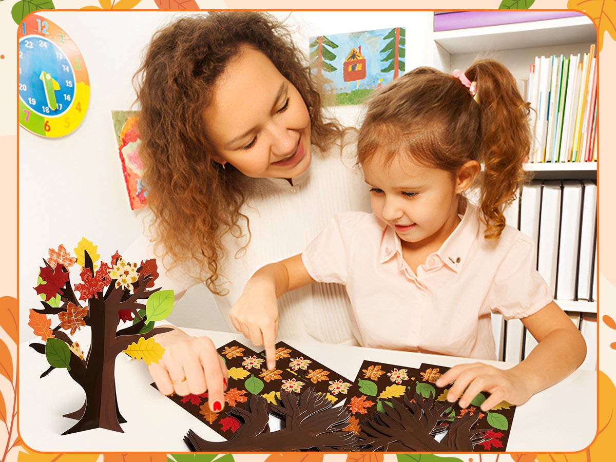 Woman and child crafting a fall tree with colorful leaf cutouts at a table.
