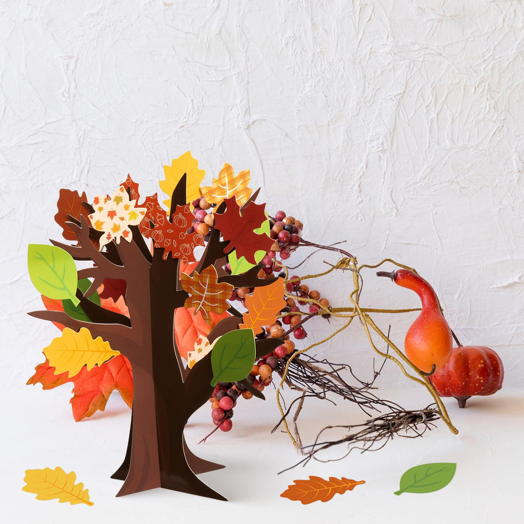 3D craft tree with colorful fall leaves and decorative berries, next to a small gourd and branches.
