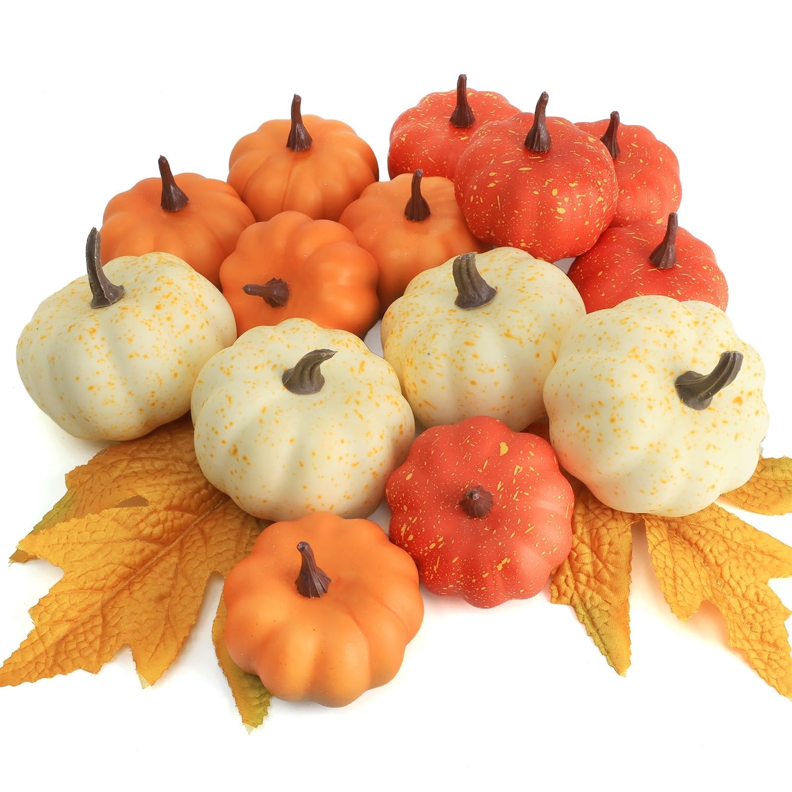 Assortment of mini artificial pumpkins in orange, white, and speckled red, with fall leaves on a white background.