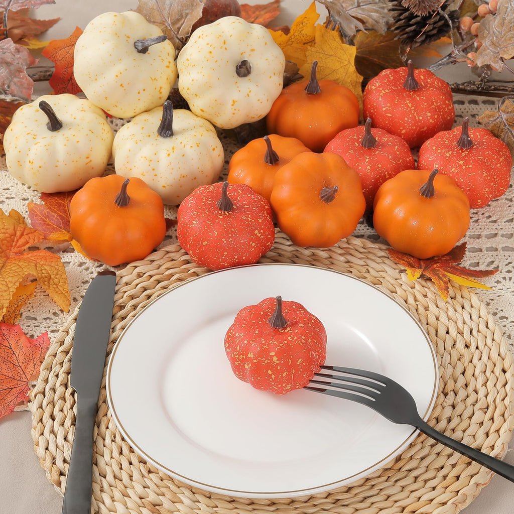 Miniature artificial pumpkins and fall leaves arranged on a table setting with a plate, fork, and knife.