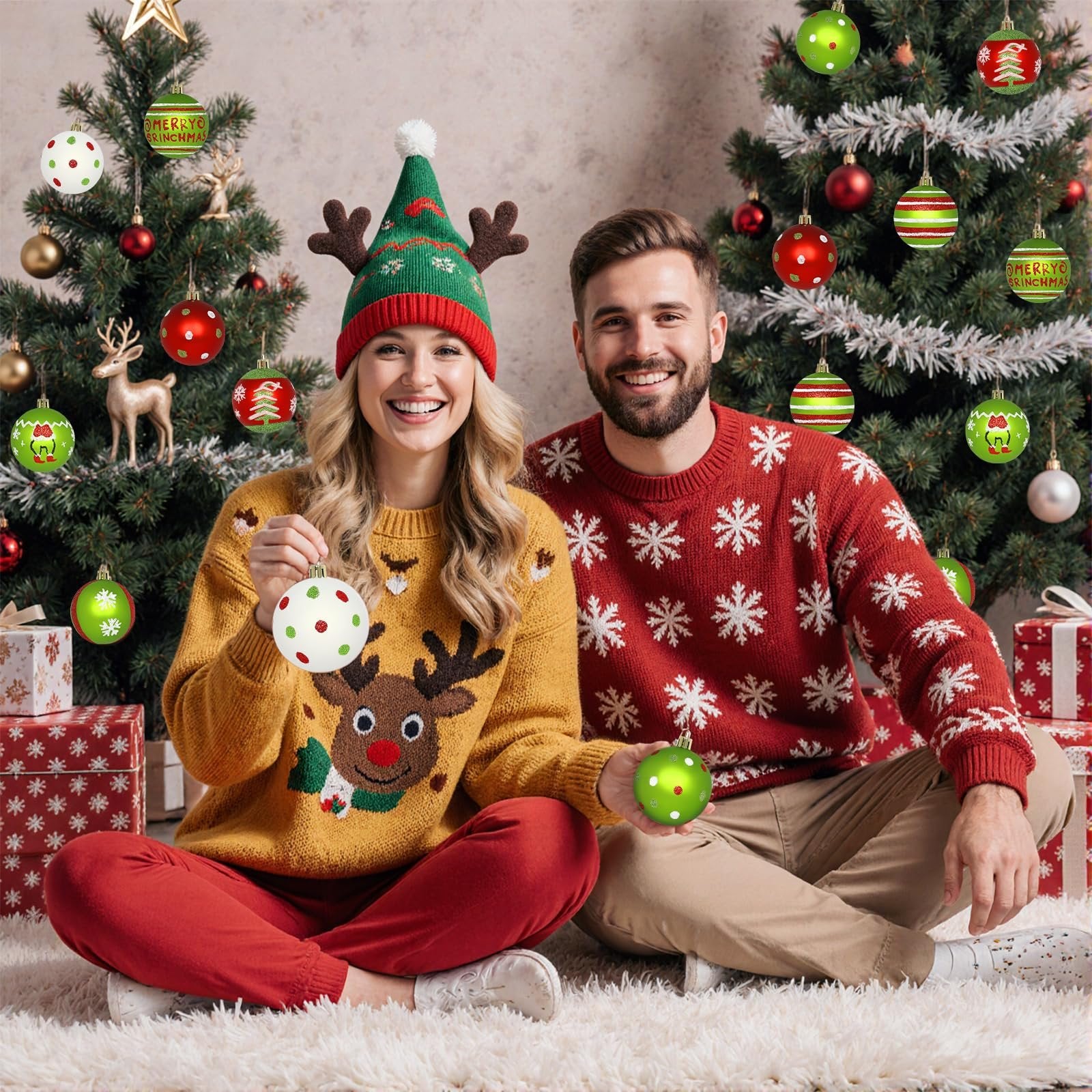 Couple in festive sweaters and hats sitting by Christmas trees holding ornaments
