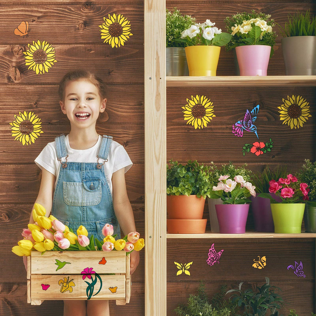 Smiling girl in denim overalls holding a wooden crate of tulips, with butterfly and sunflower stencils on a wooden wall and shelf.