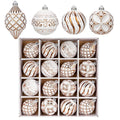 Set of 16 shatterproof Christmas ball ornaments in white with bronze hand-painted designs, arranged in a box with four individual ornaments above.