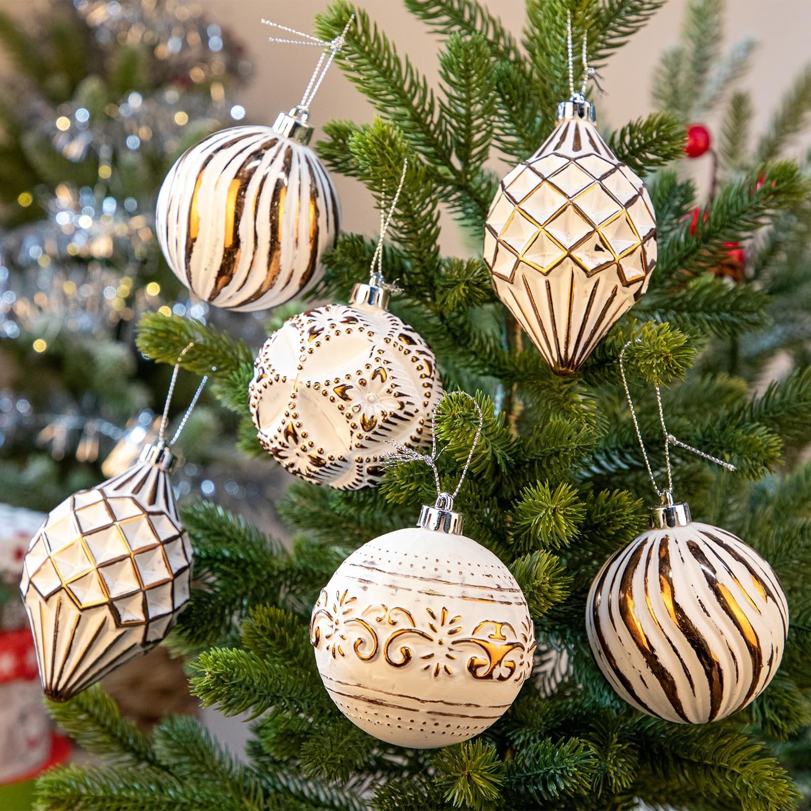 Assorted white and bronze hand-painted Christmas ball ornaments hanging on a green artificial Christmas tree.