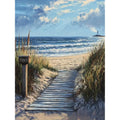 Wooden boardwalk leading to a sandy beach with ocean waves and a distant lighthouse under a cloudy sky.