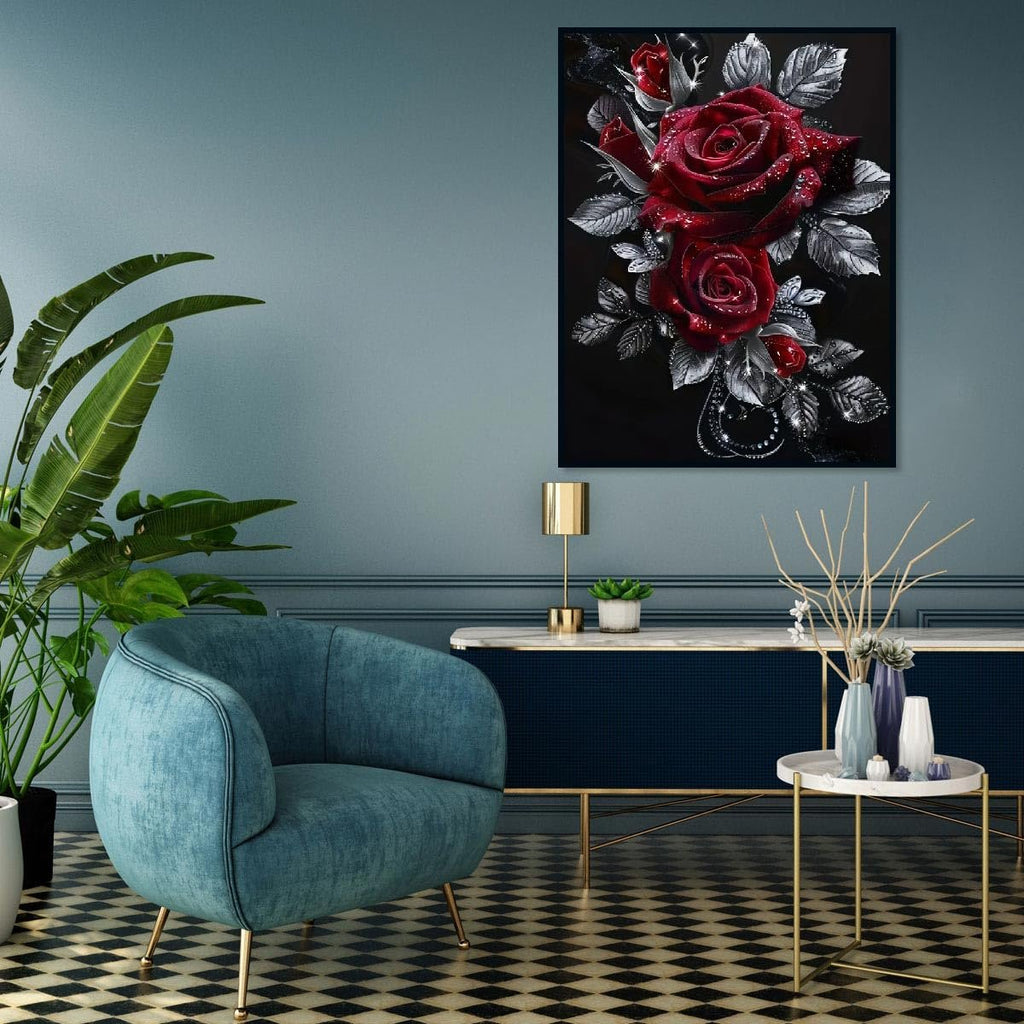 Diamond painting of red roses with silver leaves hanging on a wall above a console table with a lamp and plants.
