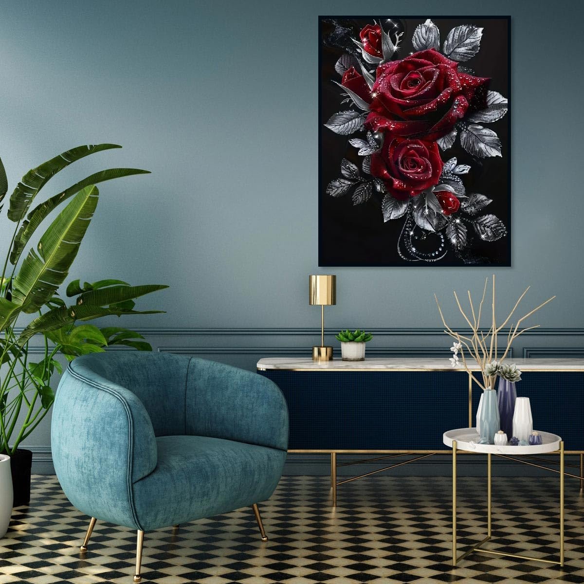 Diamond painting of red roses with silver leaves hanging on a wall above a console table with a lamp and plants.