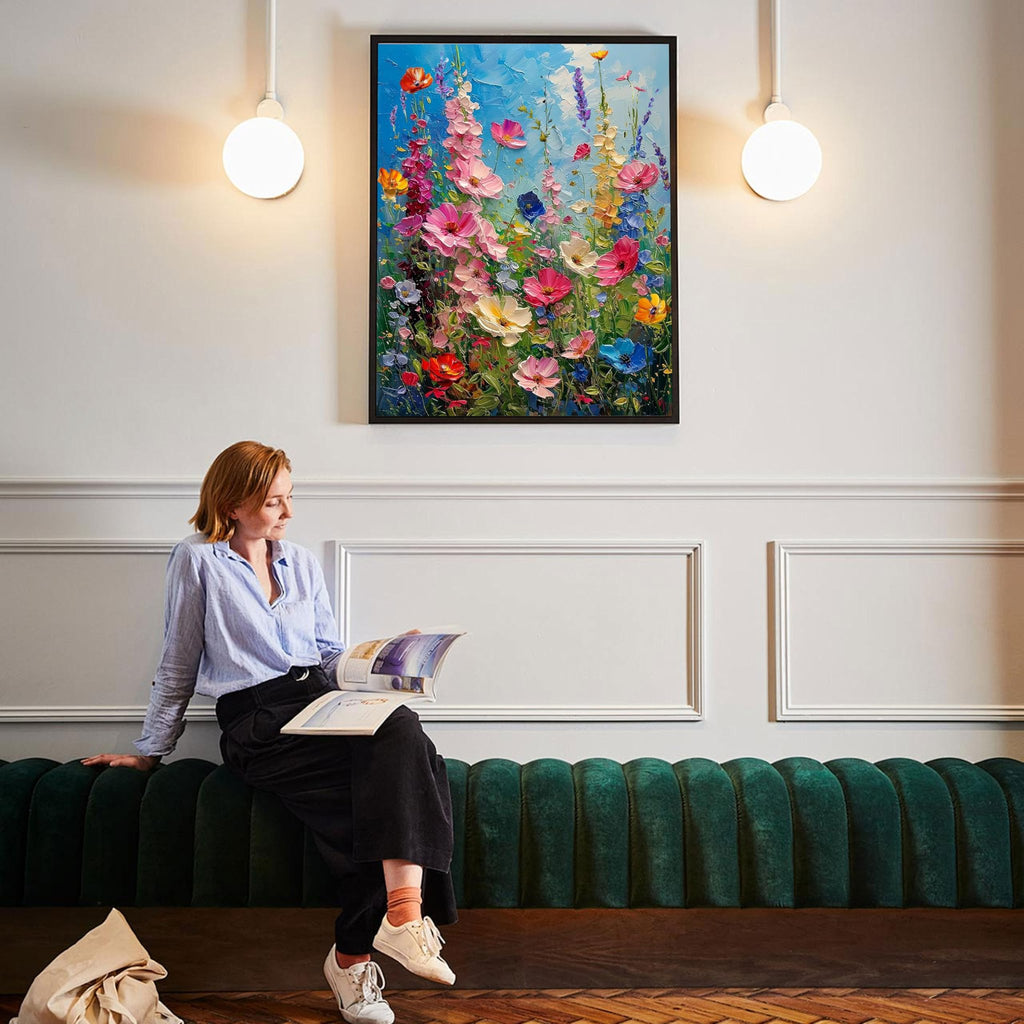 Woman reading a magazine while sitting on a green couch below a framed wildflower painting