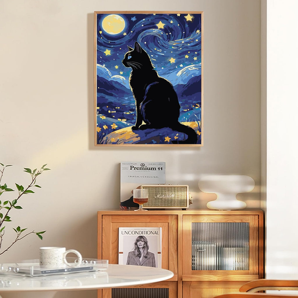 Black cat sitting on a rock under a starry night sky with a full moon, framed painting.