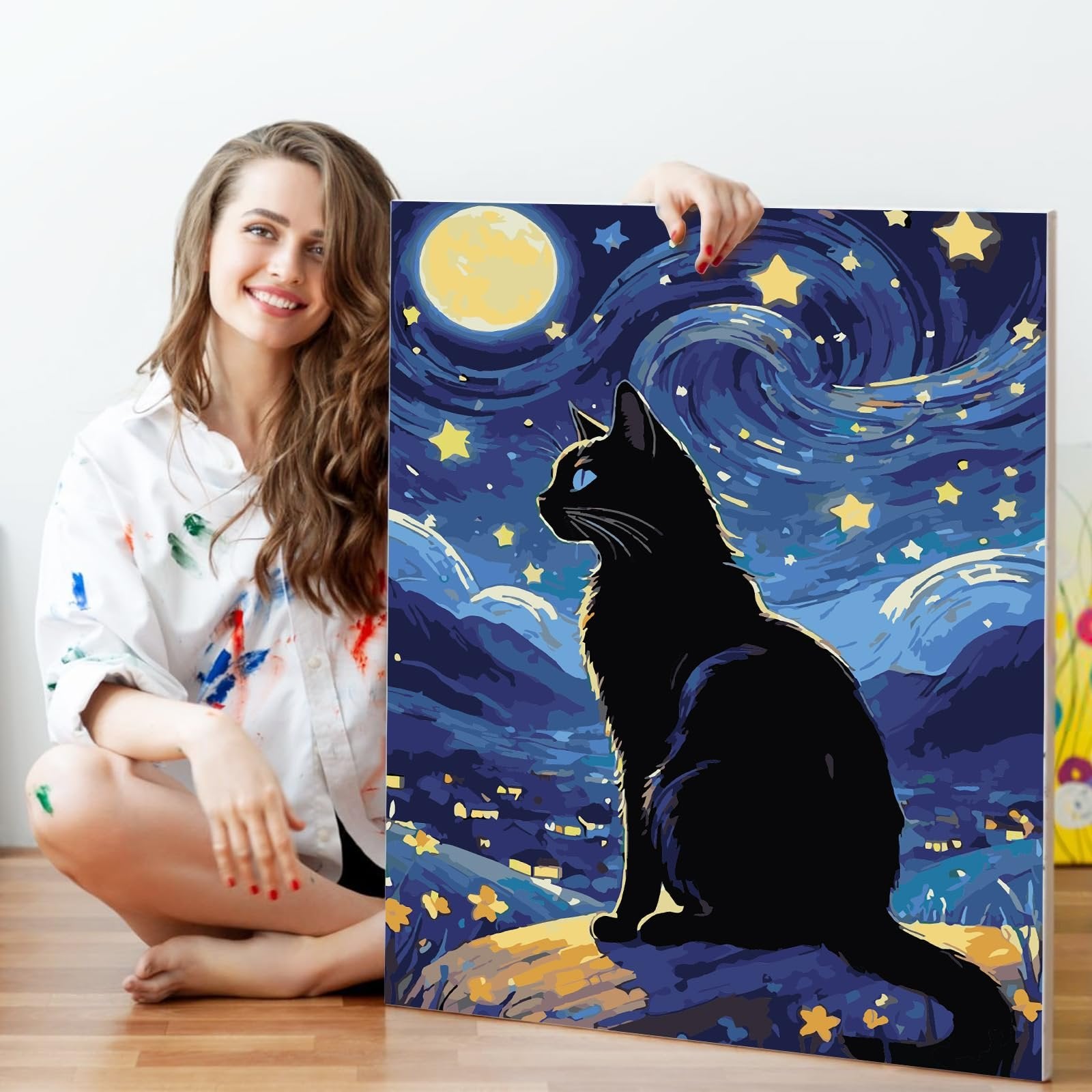 Woman holding a 16x20 inch paint by numbers kit featuring a black cat under a starry night sky with a large moon.