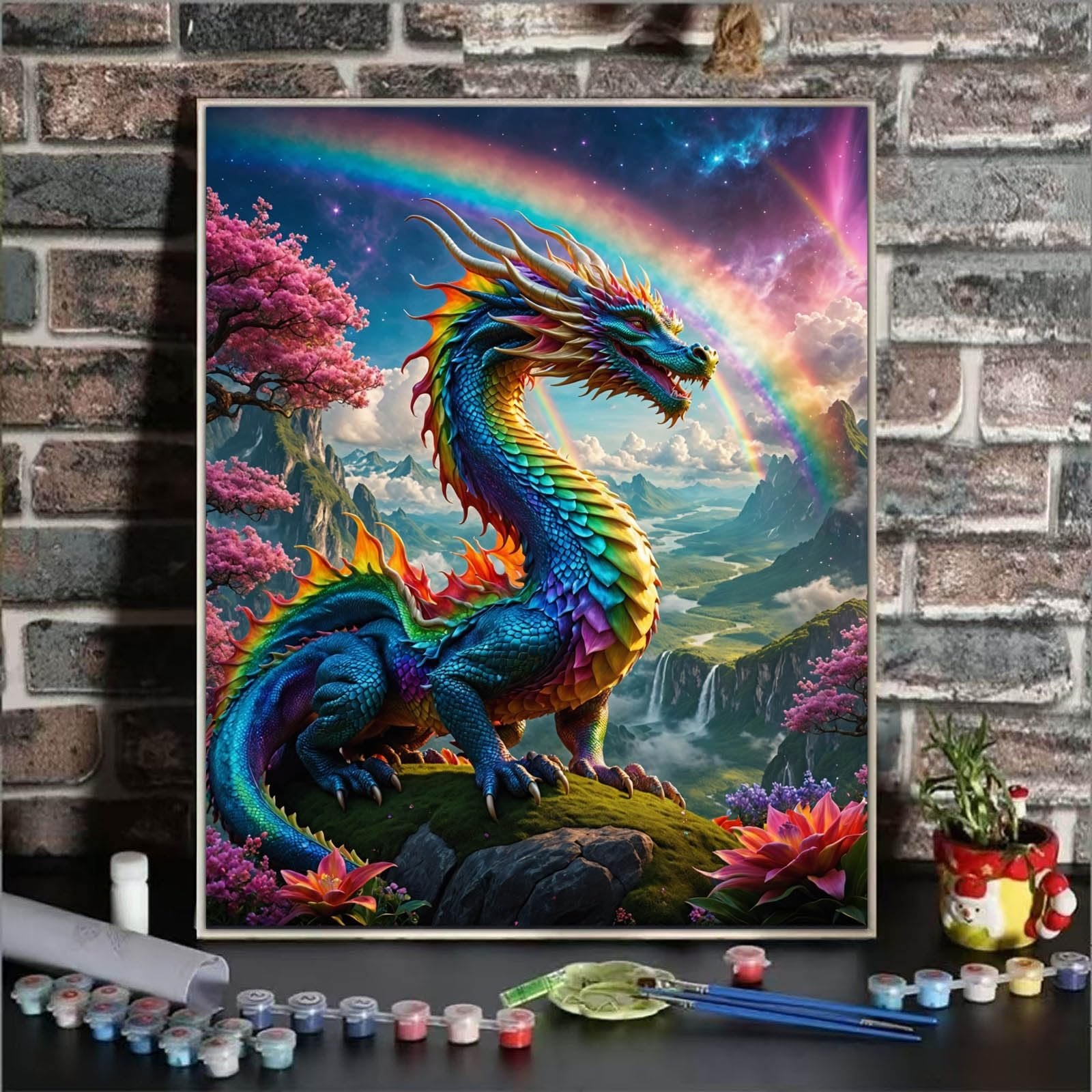 Colorful dragon perched on a grassy hill with a rainbow and waterfalls in the background, paint supplies in foreground