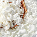 Ivory white dried rose petals and a single preserved rose in a woven basket, top-down view