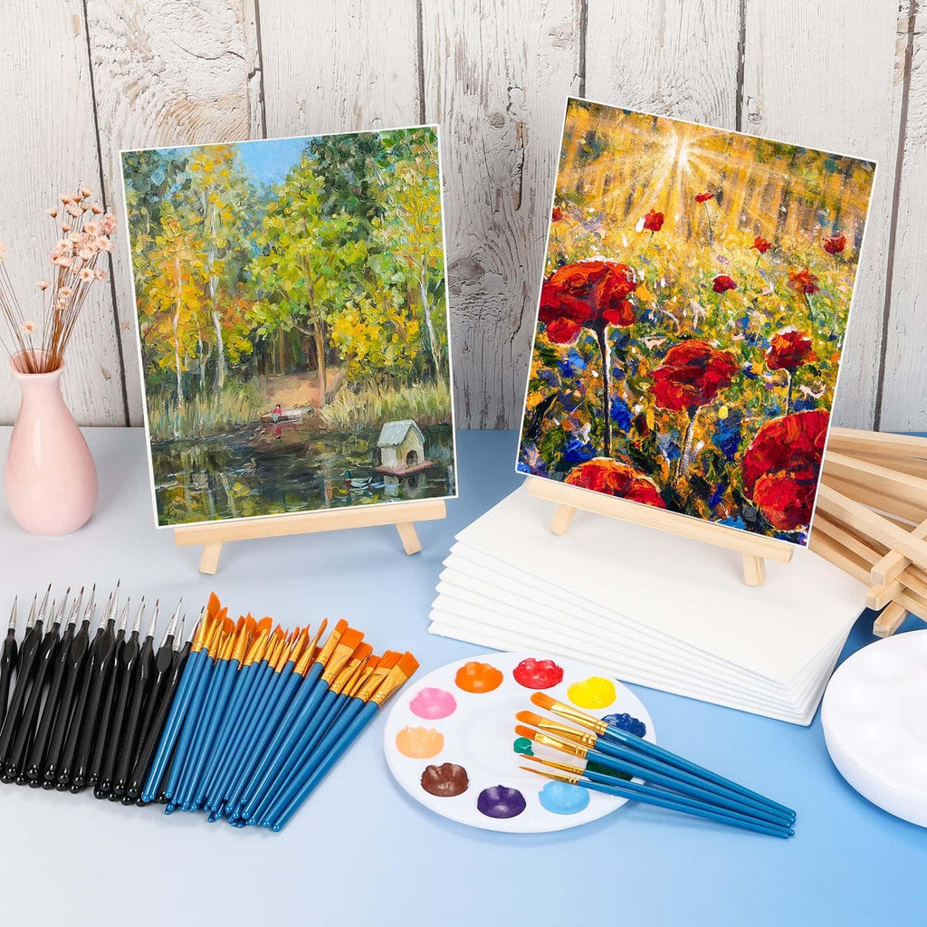 Mini painting kit with canvases, easels, brushes, and palettes on a blue surface with a wooden background.