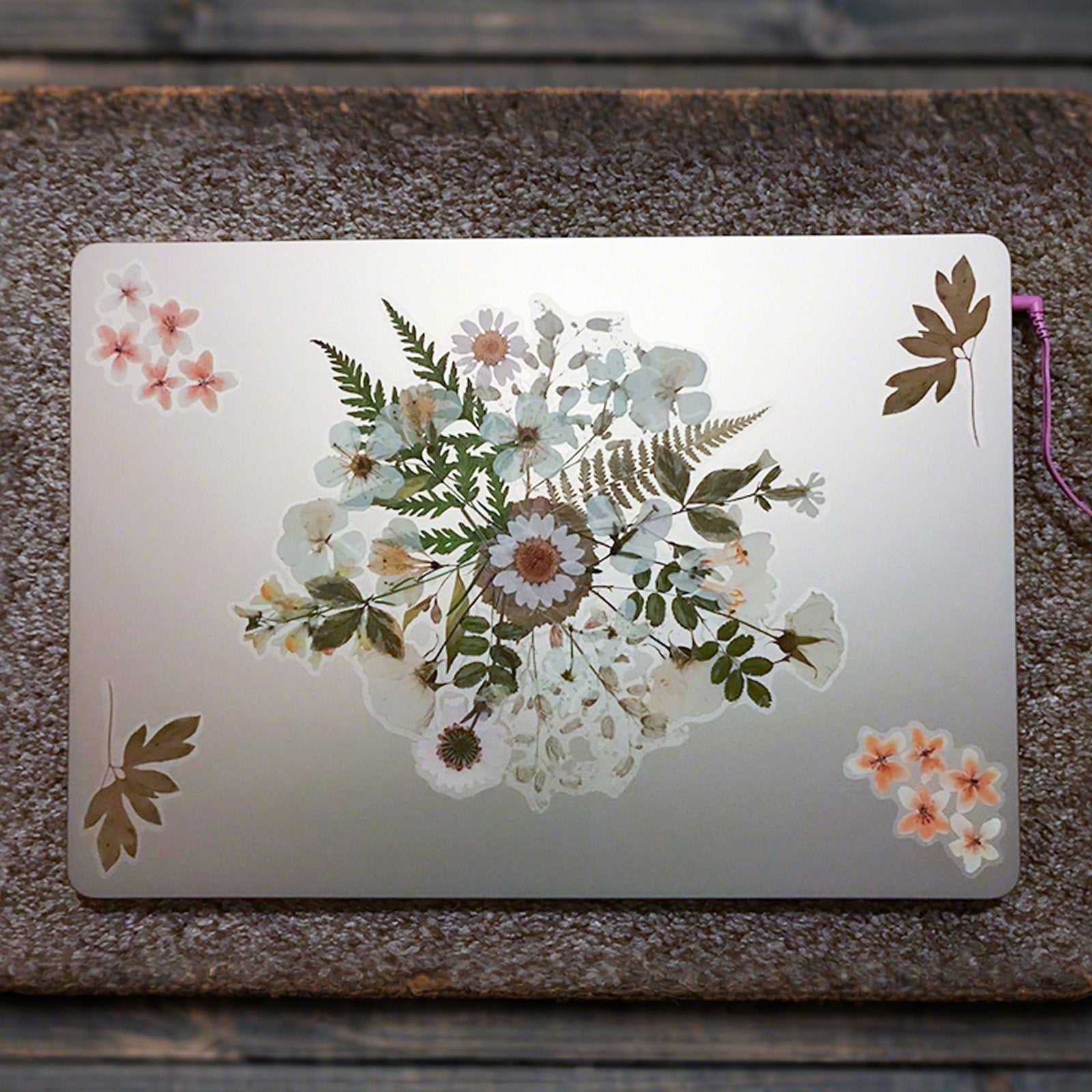 Botanical PET stickers arranged on a silver laptop lid, featuring floral and leaf designs.