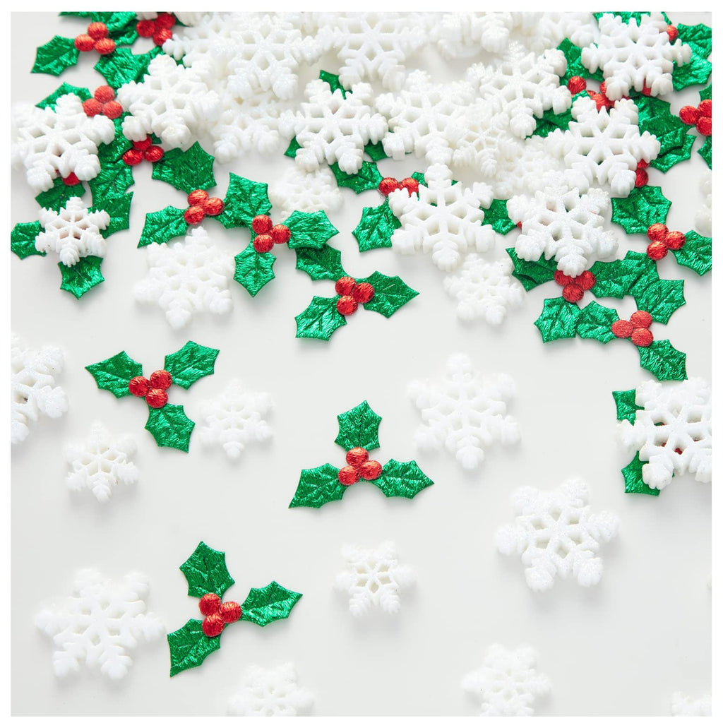 Assortment of white glitter snowflakes and green holly berry embellishments scattered on a white background.