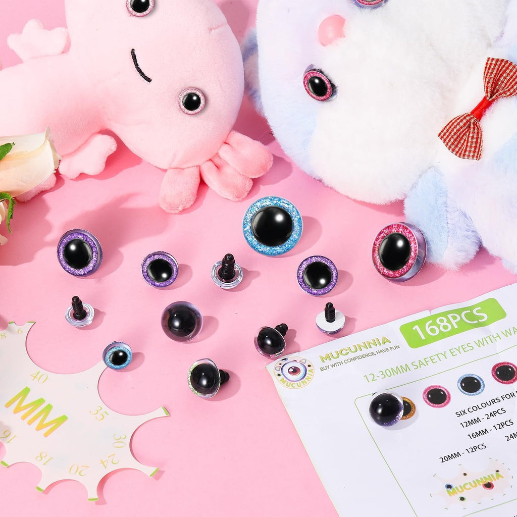 Assorted glitter safety eyes and washers scattered on a pink background with plush toys and a sizing tool.
