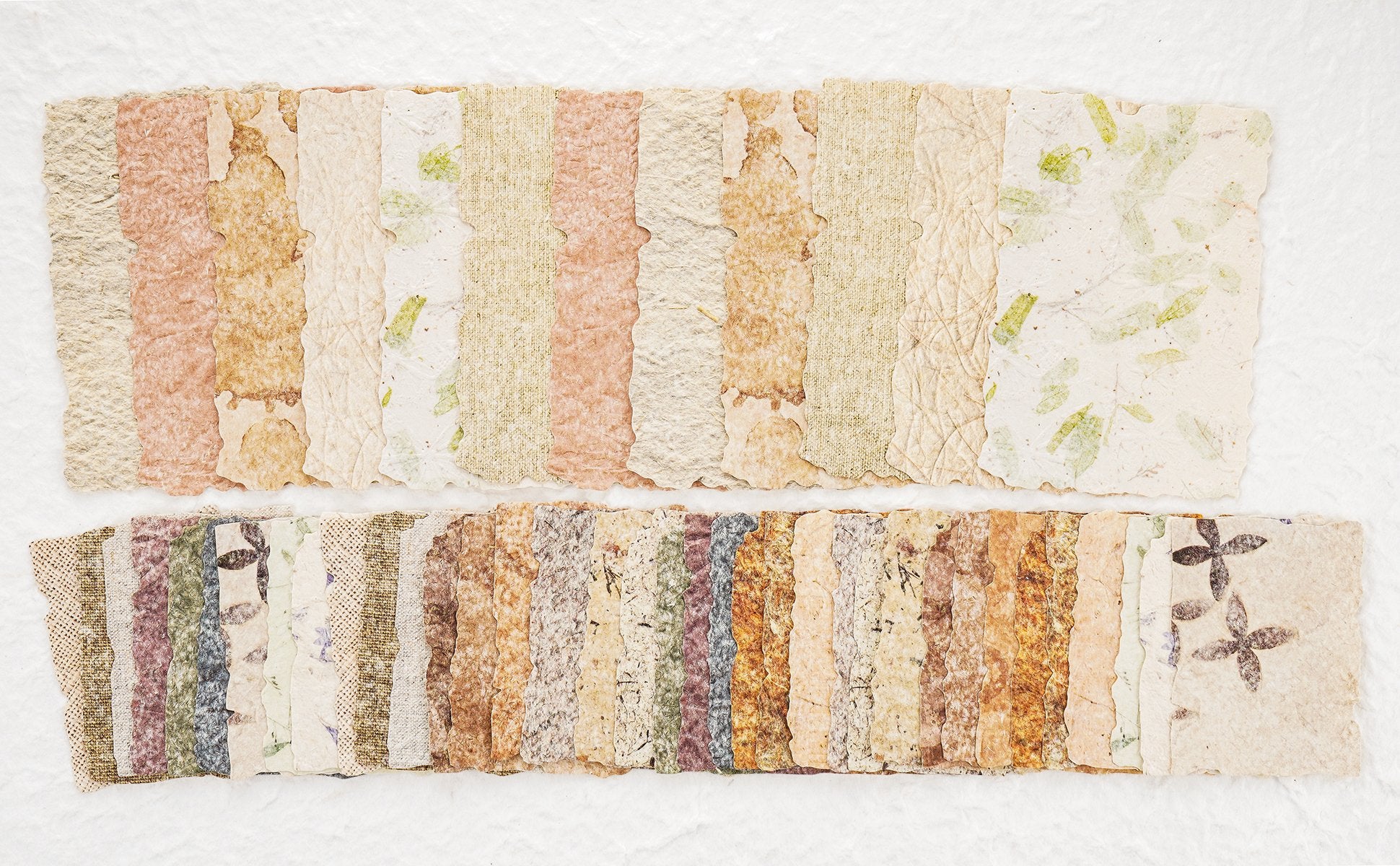Assorted textured scrapbook paper sheets with embossed patterns and botanical inclusions, arranged in two rows.