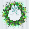 Lighted shamrock wreath with green LED lights and a white bow with shamrocks, hanging on a white door.