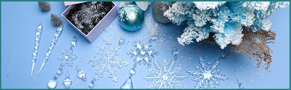 Assortment of clear acrylic snowflake and icicle Christmas ornaments scattered on a blue background with a small frosted tree and decorative baubles.