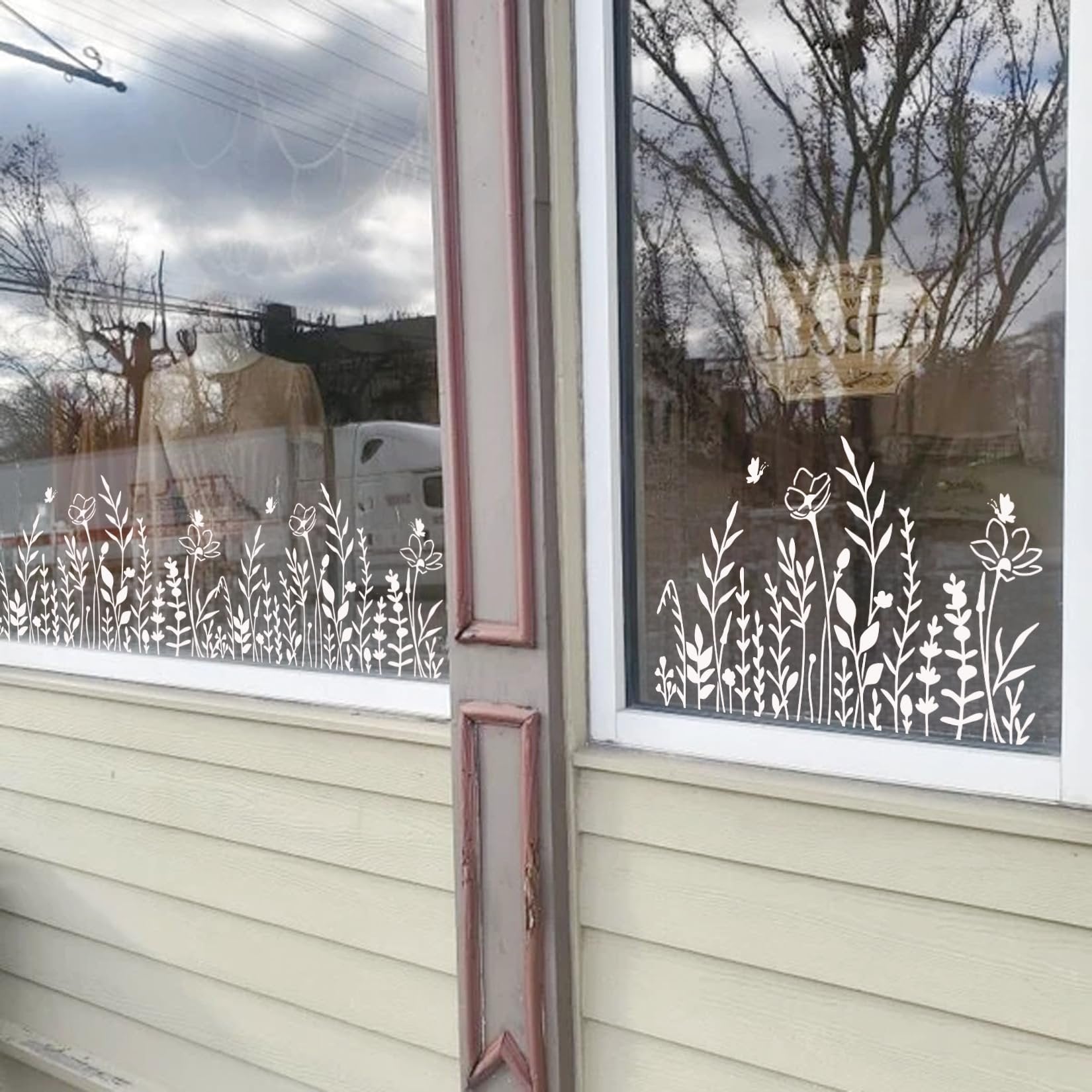 White wildflower stencils applied to a window, showing a border of various floral and plant designs.