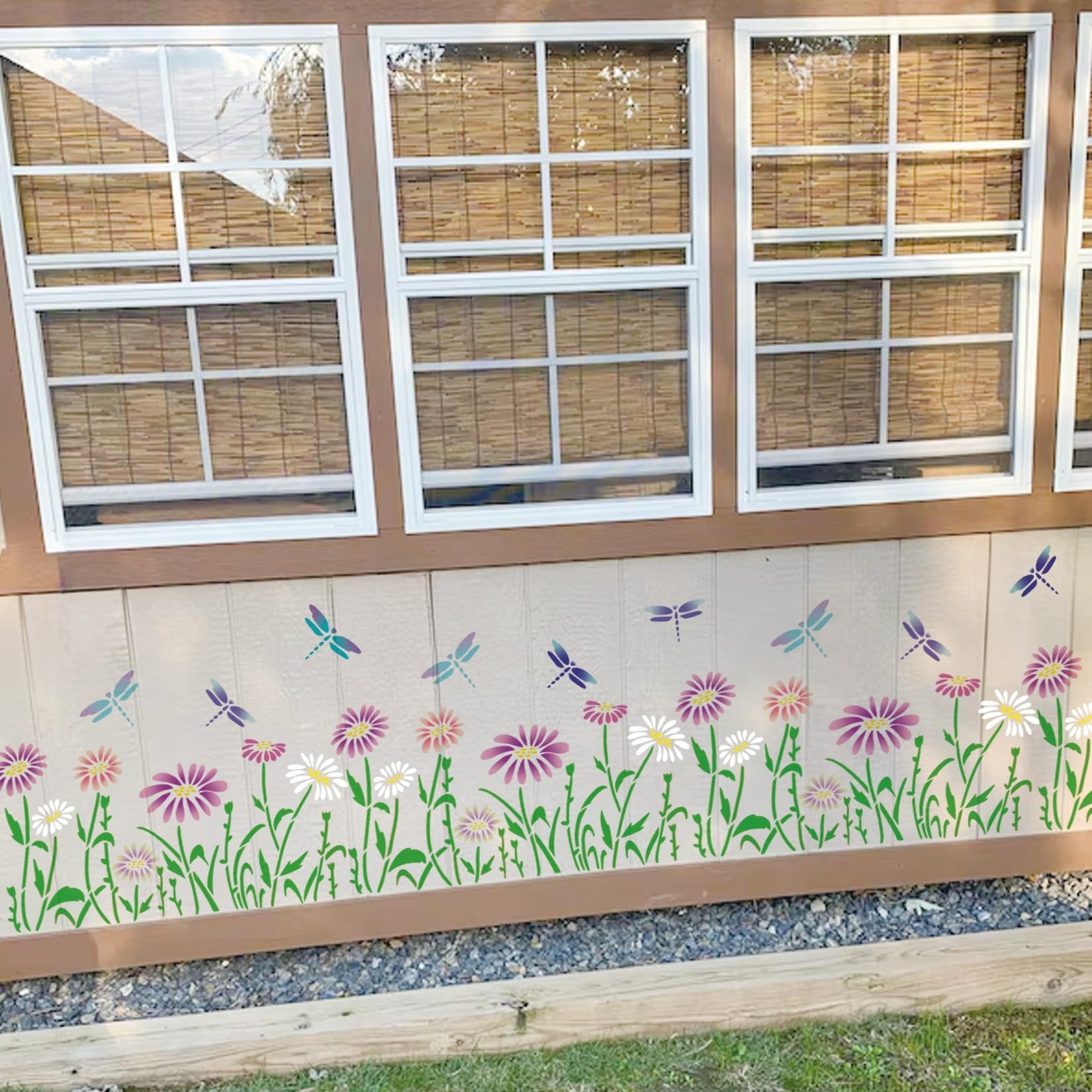 Flower and dragonfly stencil design applied to the side of a building with windows