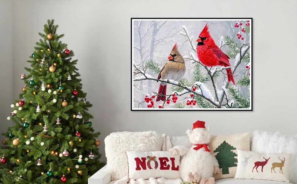 Diamond art painting of two cardinals on a snow-covered branch with red berries, displayed above a couch with Christmas decorations.
