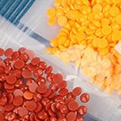Close-up of red and orange diamond art painting beads in plastic bags.