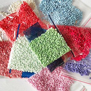 Assorted colorful diamond painting gems in plastic bags, close-up view.
