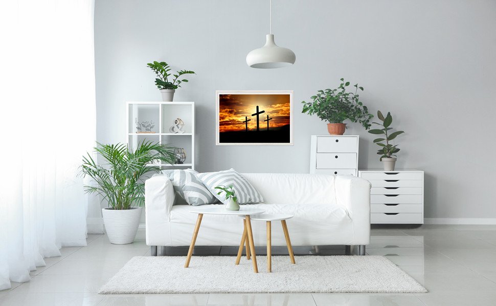 Living room with a white sofa, coffee table, and framed artwork of three crosses at sunset
