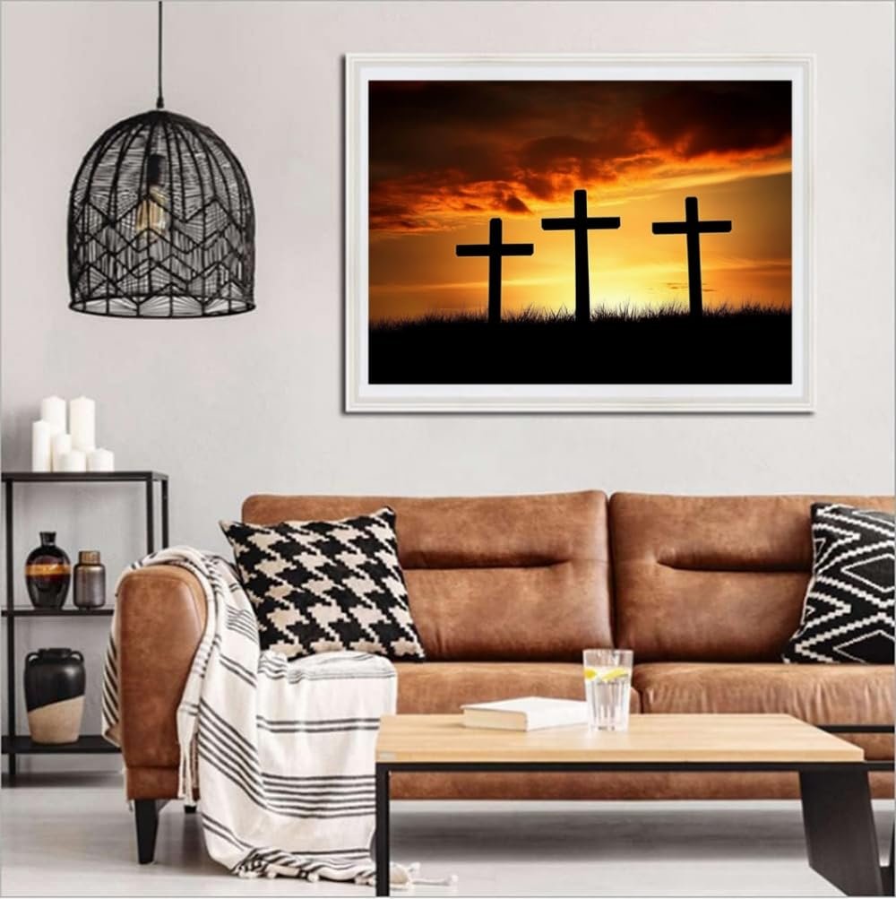 Framed diamond painting of three crosses at sunset hanging above a sofa in a living room