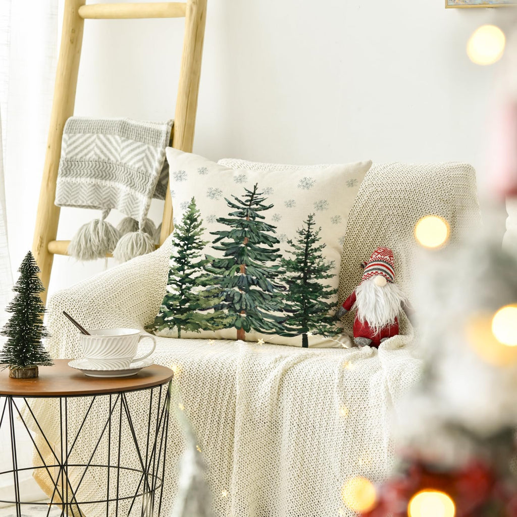 Christmas throw pillow cover with pine trees and snowflakes on a couch with a blanket and gnome decoration.