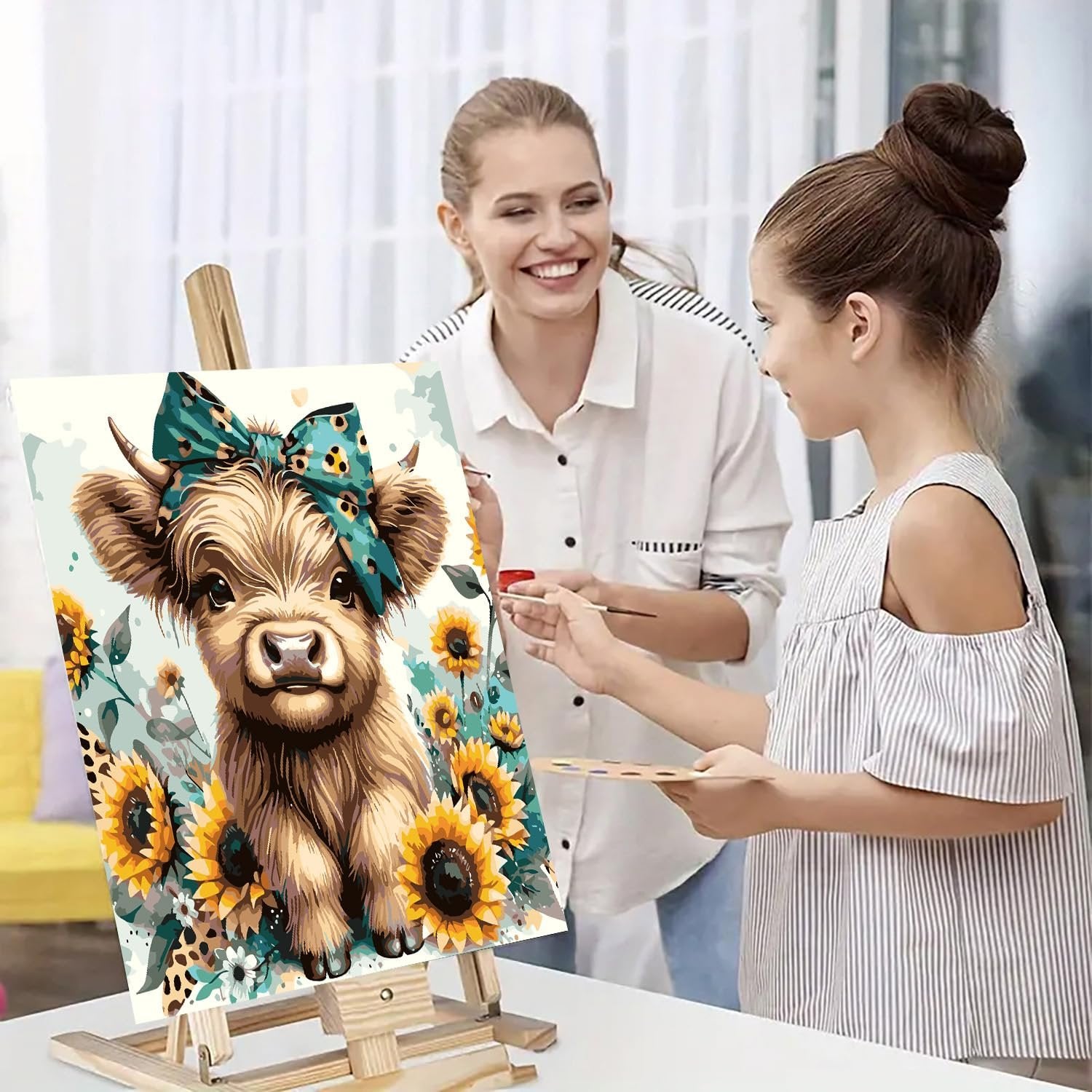 Mother and daughter painting a cow with sunflowers on an easel, enjoying a creative activity together.