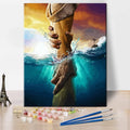 Paint by numbers kit showing Jesus reaching down to help someone out of the water, with paints and brushes in foreground.
