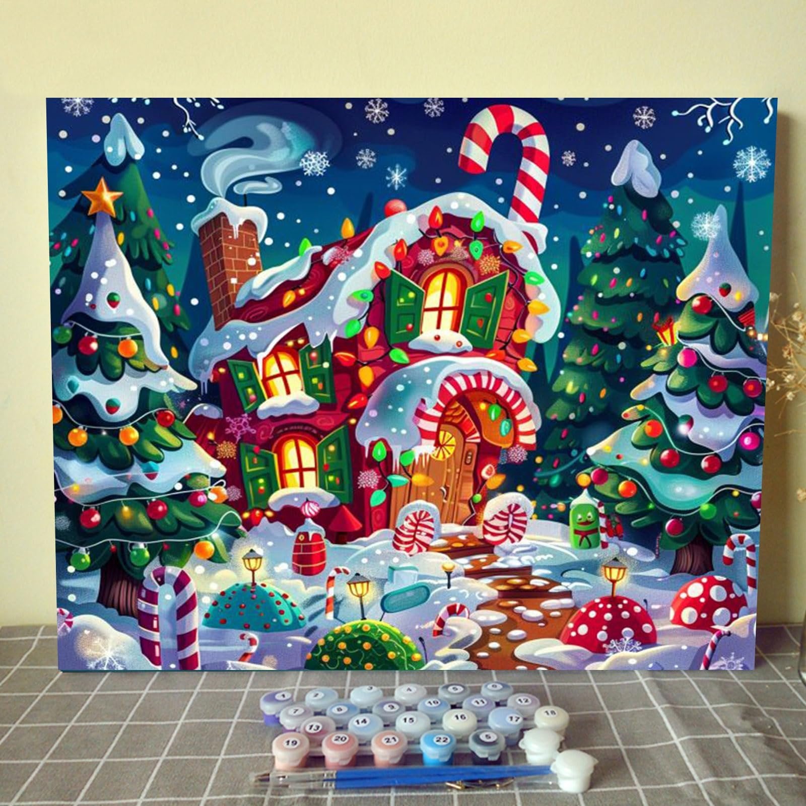 Christmas candy house paint by numbers kit with trees, snow, and candy canes, with paint pots and brushes in foreground.