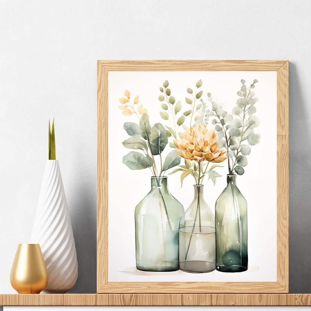 Watercolor painting of a yellow flower and greenery in three glass vases, framed in wood.